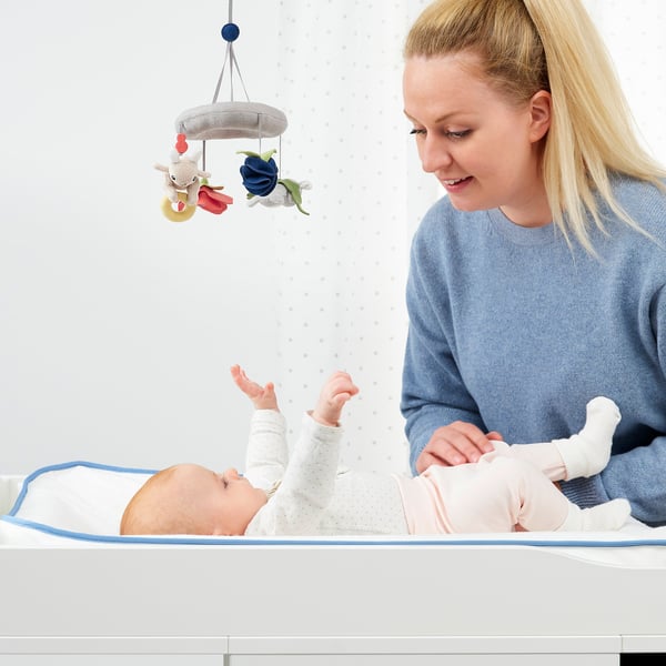 Woman & baby play with nature mobile over changing table.