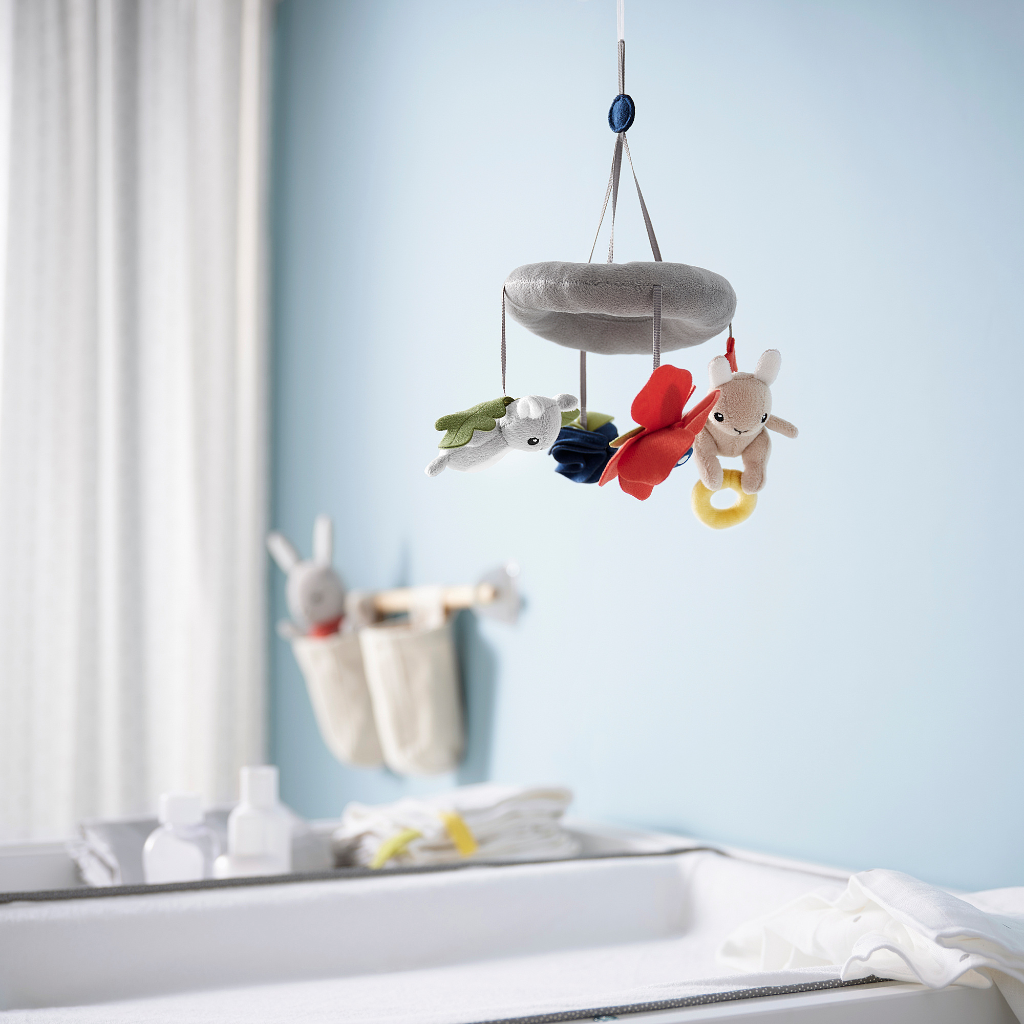 GULLIGAST mobile with soft nature-inspired figures hangs near changing table.