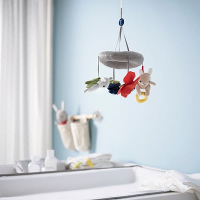GULLIGAST mobile with soft nature-inspired figures hangs near changing table.