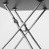Black and white close-up of metal table leg joints. Sturdy, adjustable design with screws visible, emphasizing durability and precision engineering.