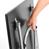 A person folds a metal table using a handle, showcasing its compact storage feature.