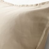 Close-up of beige cotton cushion cover, showcasing smooth texture and neat stitching for quality detail.