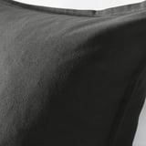 Black cushion cover made of smooth cotton, displayed indoors, illustrating its texture and quality.