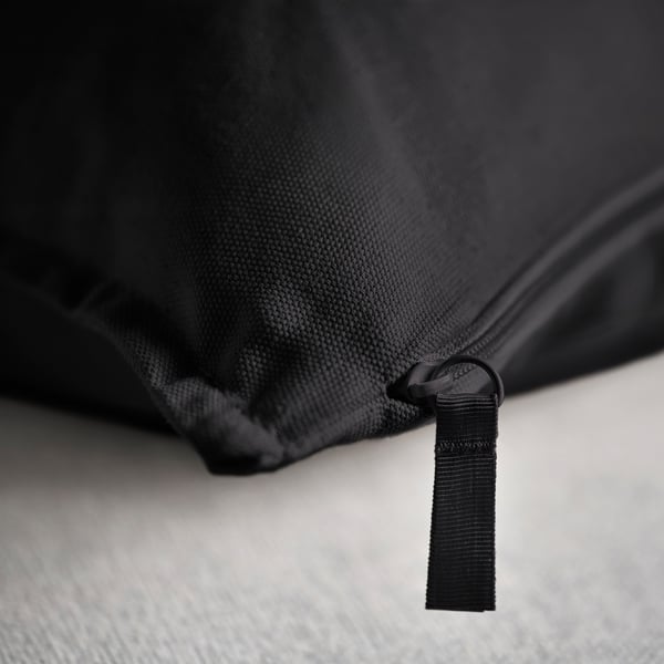 Close-up: black cushion cover with quality zipper, textured fabric, likely cotton.