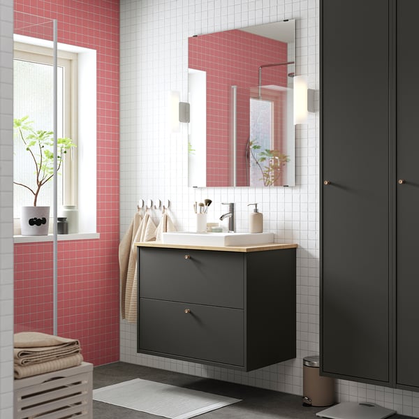 Modern bathroom with red HAVBÄCK vanity, dark drawers, wood countertop, white sink, and mirror by window with plants.