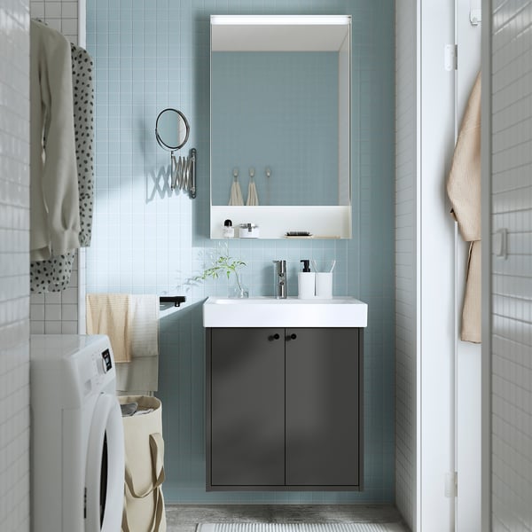 Modern bathroom with grey HAVBÄCK vanity, sink, mirror, washing machine, and blue tiles.