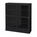 A black HAVSTA display cabinet made of pine with glass doors and shelves, exhibiting a sleek, rectangular design.