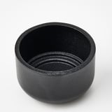 Black, round, metallic candle holder with textured finish.