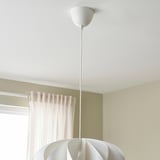 A modern pendant lamp hangs from a ceiling hook, featuring a sleek, white shade with multiple layers, attached by a thin cord.