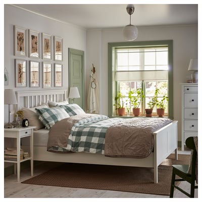 Cozy bedroom with HEMNES white wood bed, green accents, featuring potted plants, checkered blankets, and framed wall art.