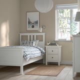 HEMNES bed, blue checkered bedspread, nightstand with lamp, books, clock, sunny window.