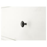 Close-up of metal hook affixed to white wall, secured firmly for hanging items.