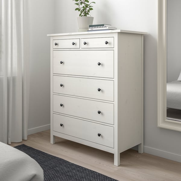 Modern white HEMNES chest with six drawers in a minimalist bedroom.