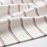 Stacked white cloths with red and black striped edges folded neatly, showcasing quality texture and design.