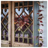HÖSTAGILLE bouquet hangs on rustic door, vivid autumn colors, artificial leaves and flowers, compact yet detailed, part of larger decor collection.