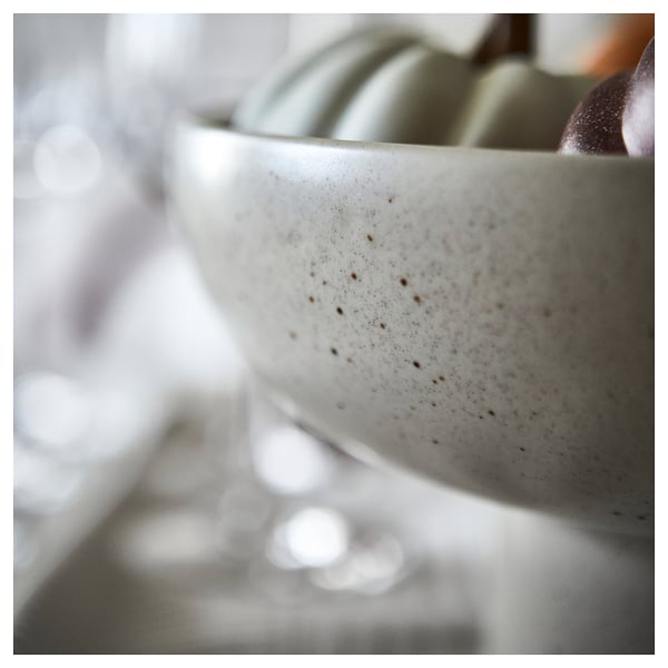 Close-up of a speckled light beige serving bowl in stoneware, showcasing its smooth texture and decorative design.