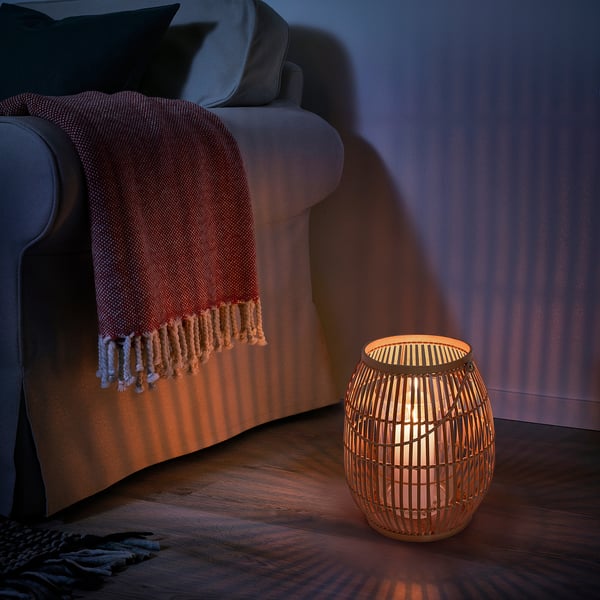 Cozy living room with HÖVISK bamboo lantern near gray chair, blanket.