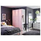 Modern bedroom with light pink closet, black and white bedding, large mirror, black rug, and green lamp shade.