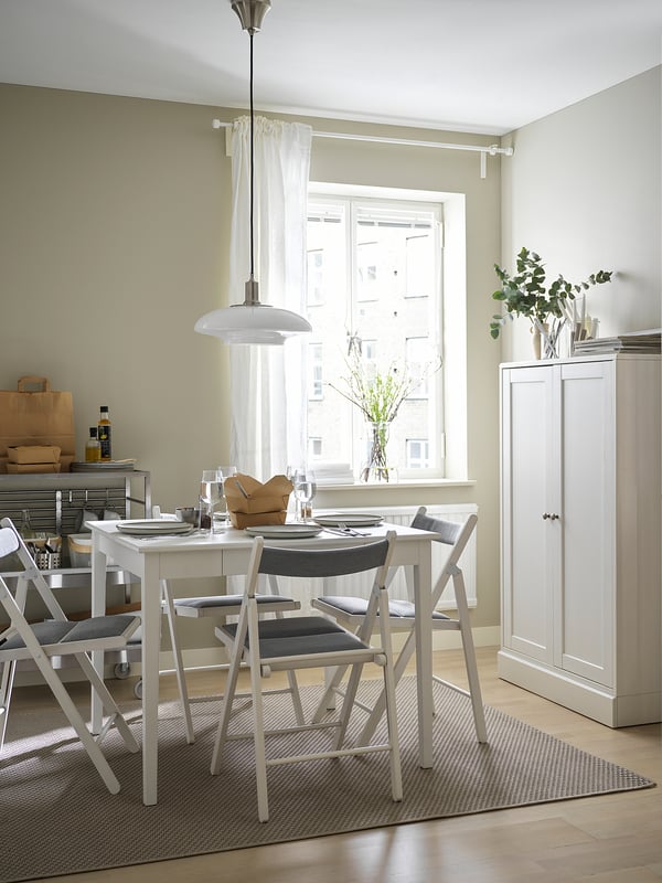 Modern dining room with IDANÄS white table, gray chairs, large window, pendant light, and cabinet.