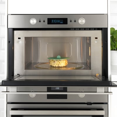 Stainless steel IKEA microwave with vacuum-sealed glass bowl inside, showcasing its food storage and heating function.