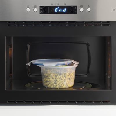 A transparent plastic container with a lid in a microwave, used for storing and reheating food. The lid clips shut for leak-proof security.