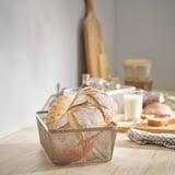 IKEA 365+ mesh food basket holds bread, smaller than glasses, on wooden table.