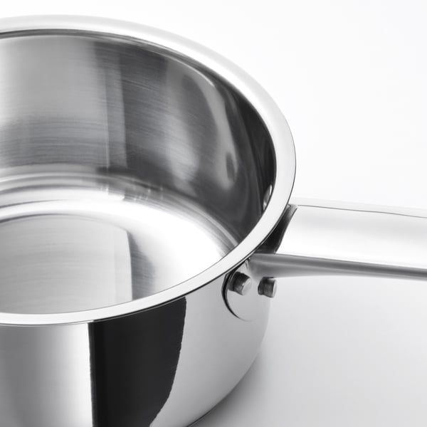 Stainless steel saucepan with thick base, suited for induction hobs and ovens. Shiny, sleek finish, reflecting light.