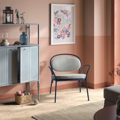 ISMANTORP armchair, grey, soft fabric, rounded metal frame, mid-sized, cosy, near storage unit, light pink walls.