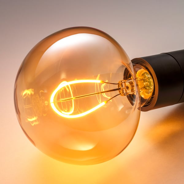 Warm glowing led bulb with brown cover, intricate filament, vintage style.