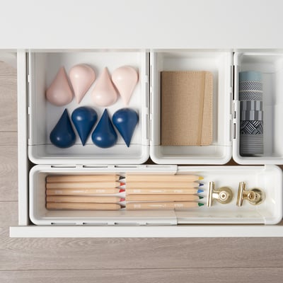 Organized drawer with extendable boxes storing office supplies.