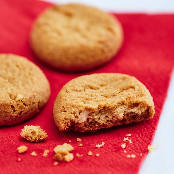 Three ginger cookies with almond crumbs on red cloth.