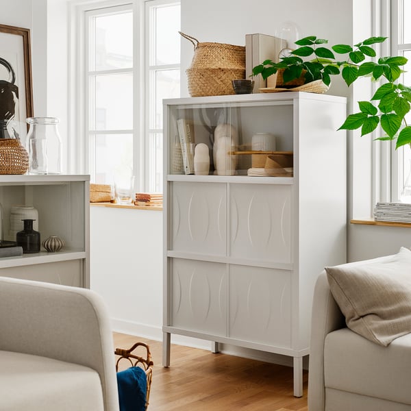 Modern living room with white KALKNÄS cabinet, textured doors, glass display, and sofa. Decor includes vases, books, and plants.