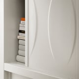 White KALKNÄS cabinet with sliding glass doors, showing neatly stacked books. Modern, minimalist design.