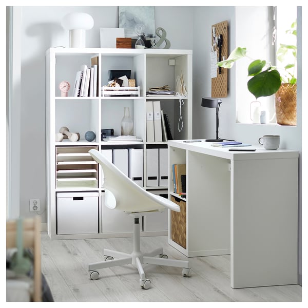 Minimalist home office with KALLAX shelves, desk, chair, lamp, and plants.