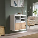 Modern living room with KALLAX shelf, books, decor, plant, sofa, table, and clock.