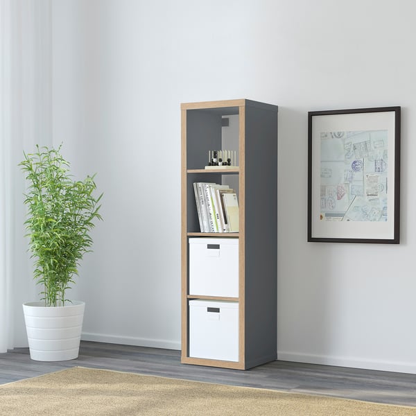 KALLAX shelf in dark gray with light wood trim, holding storage boxes, books, and a plant.