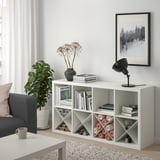 KALLAX shelf in modern living room with books, lamp, dried flowers, art, fabric, yarn, couch, pillow, plant.