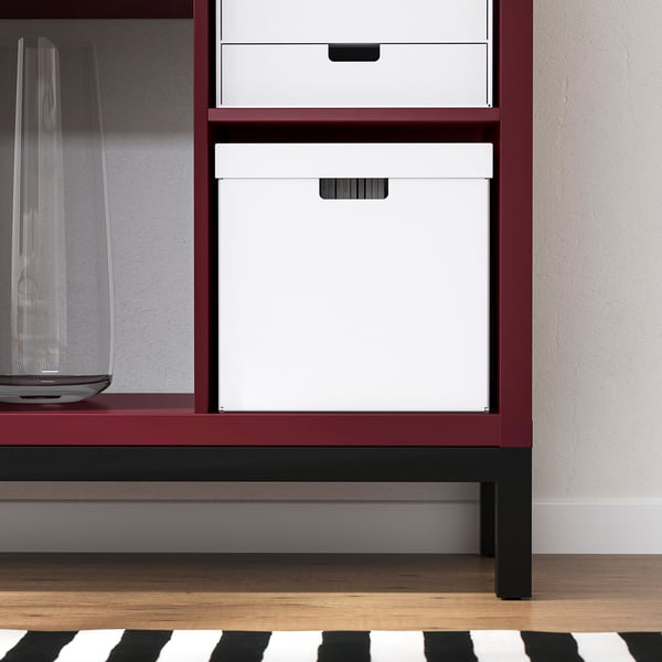 Red KALLAX shelving unit with white boxes and clear vase on lower shelf.