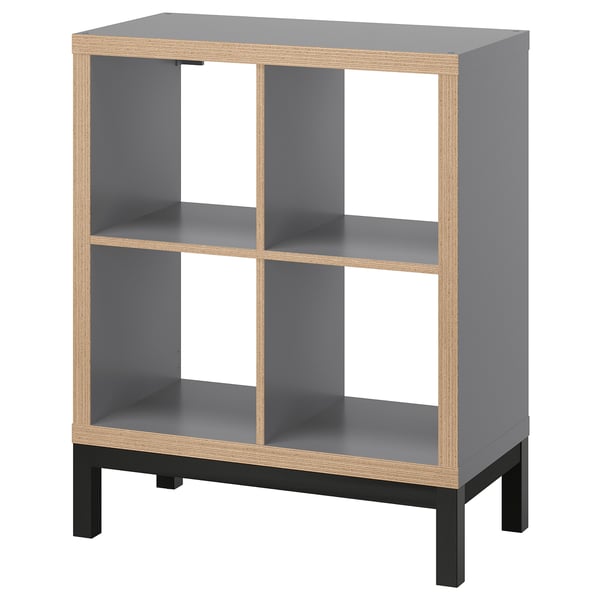 KALLAX gray shelf unit, four cube compartments, sleek modern design with light wood trim and black base, versatile for various uses.