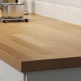 A wooden kitchen countertop with a metal pan on a stove, showcasing the worktops durability and practical use.