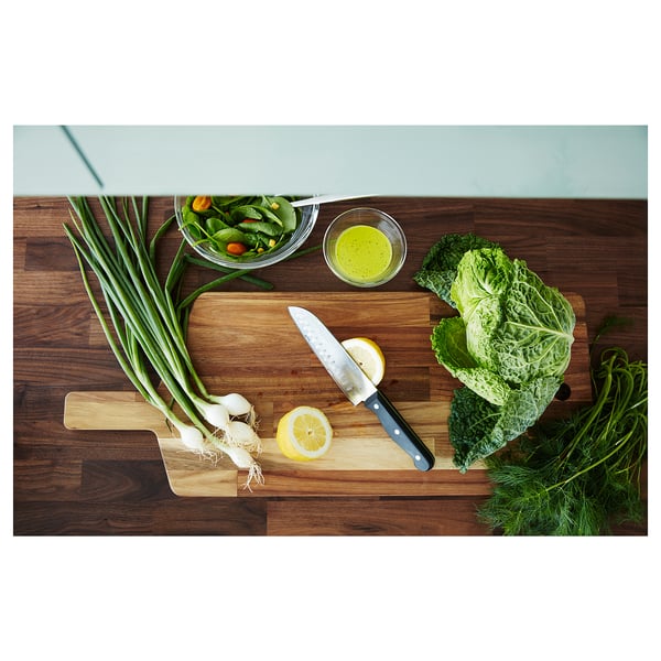 Wooden kitchen worktop, KARLBY, with walnut veneer. On it: cutting board, salad bowl, dressing bowl.