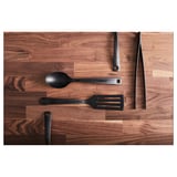 Black cooking utensils - spoon, spatula, knife - on wooden surface.