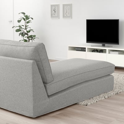Modern minimalist living room with grey KIVIK chaise, white tv stand, and black flat screen tv. Light wood flooring, and a small plant adds greenery.
