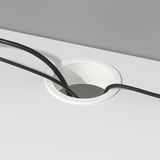 White desk with circular cable outlet, holding black cables, aiding organization and accessibility.