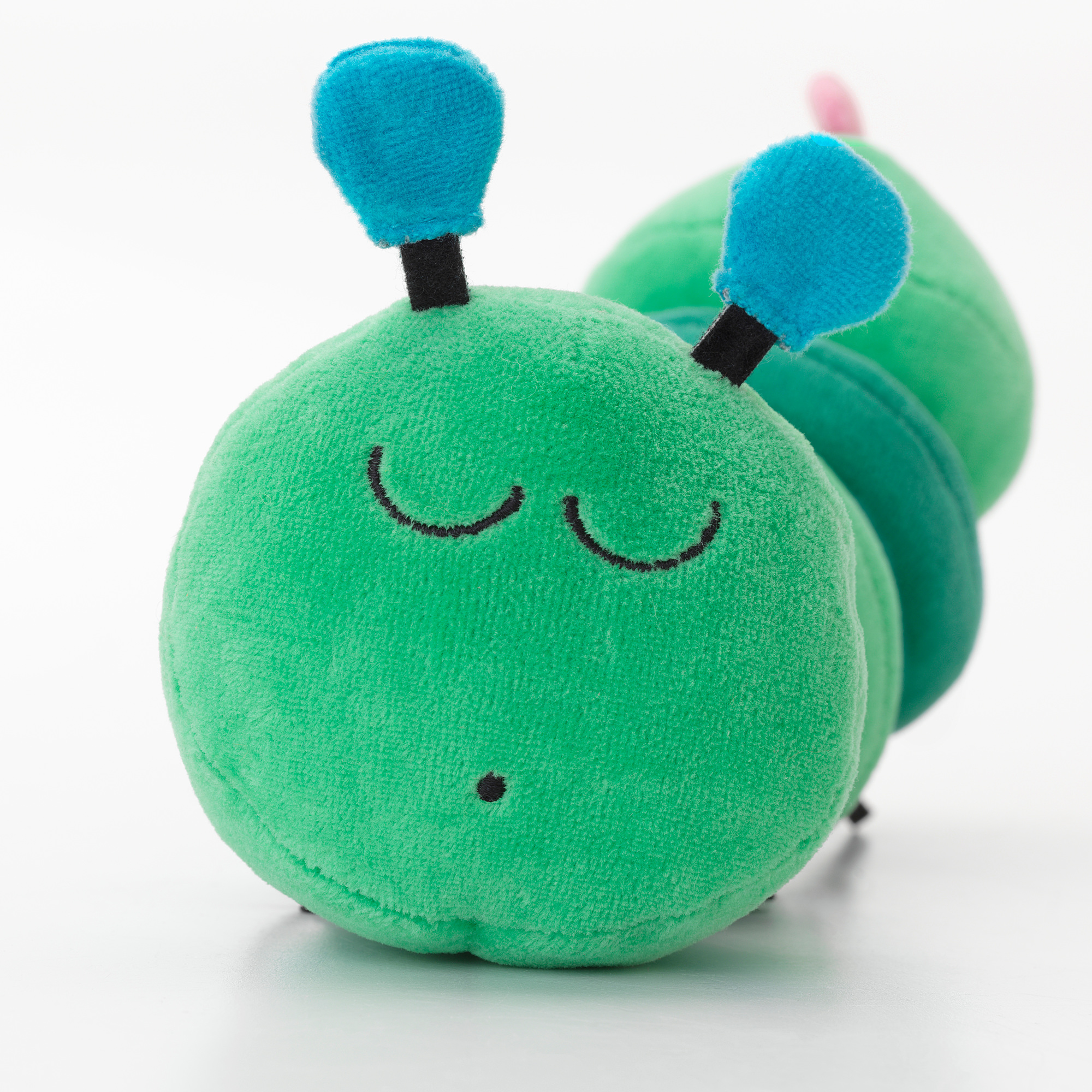 Stuffed green worm toy with blue antennae, emitting soothing sounds. Ideal for baby sensory development.