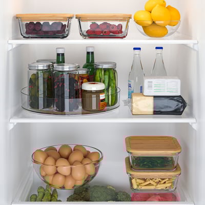 Organized fridge with turntable holding pickles, cheese, bottles. Fruit & veg in glass containers.