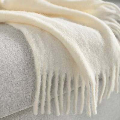 This image shows a KLIPPOXEL off-white recycled polyester throw blanket, soft, with a fluffy surface and fringed edges.