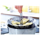 Silver KLOCKREN steamer on stovetop, lifting with dumplings inside.