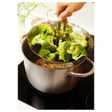 Hand lifting broccoli with tongs from steamer.