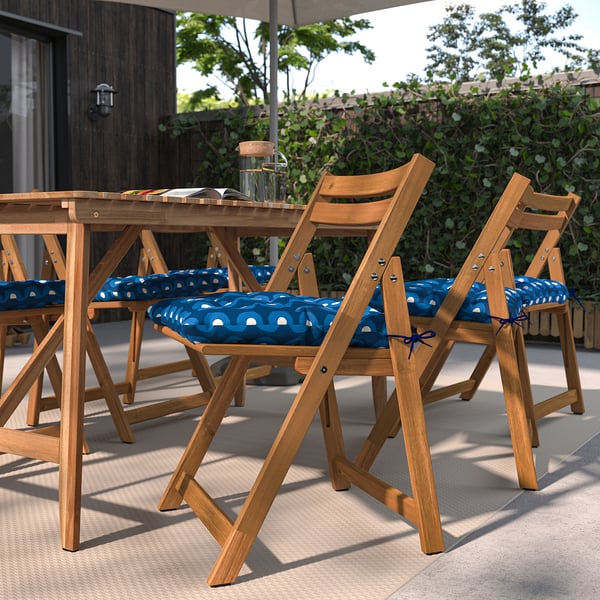 Outdoor: KLÖSAN folding chairs with blue cushions in garden setting. Wooden chairs with tie-on cushions.